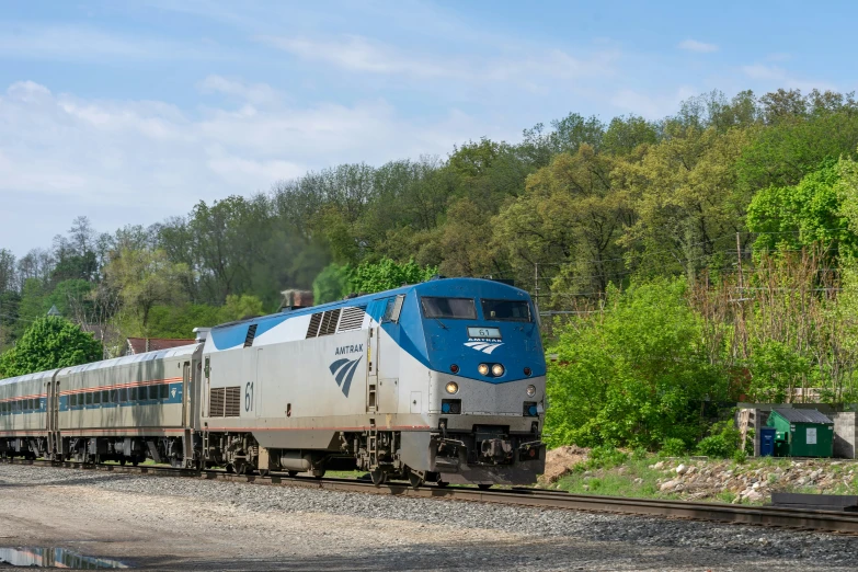 the blue and white train is traveling down the tracks