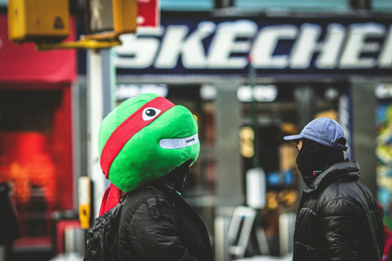 two people wearing beanies are on the sidewalk