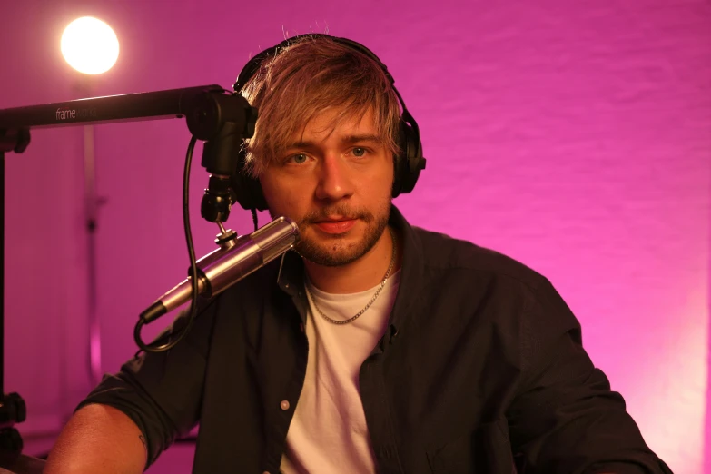 man sitting in front of microphone in recording studio