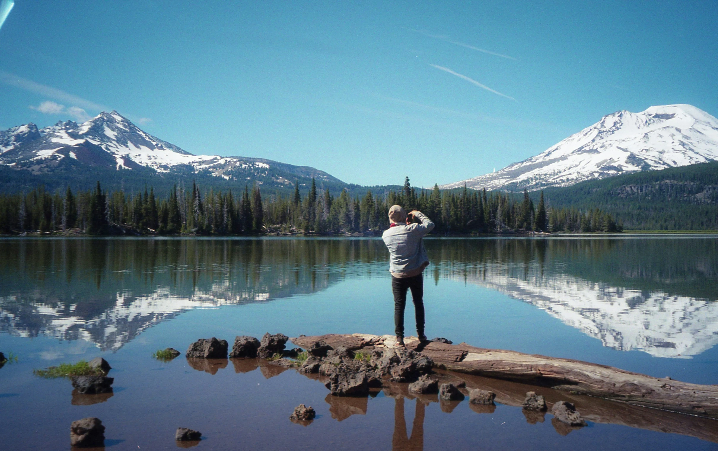 person taking pos of the mountains from a rock - covered lake