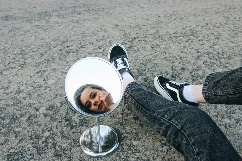 a woman sitting on the ground looking into a mirror