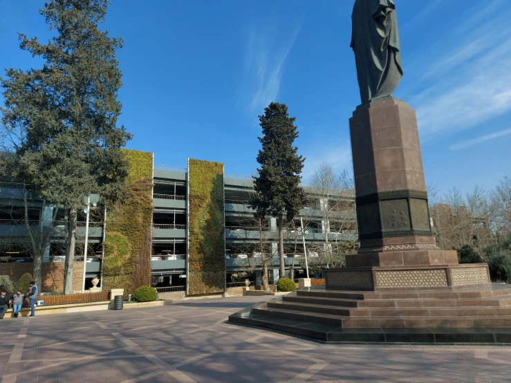 statue of a man with a beard standing in front of some buildings