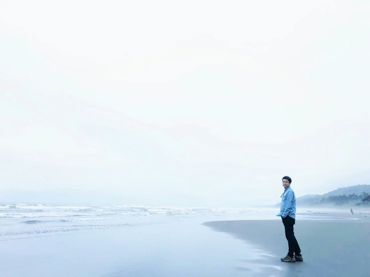 man walking on wet beach next to ocean