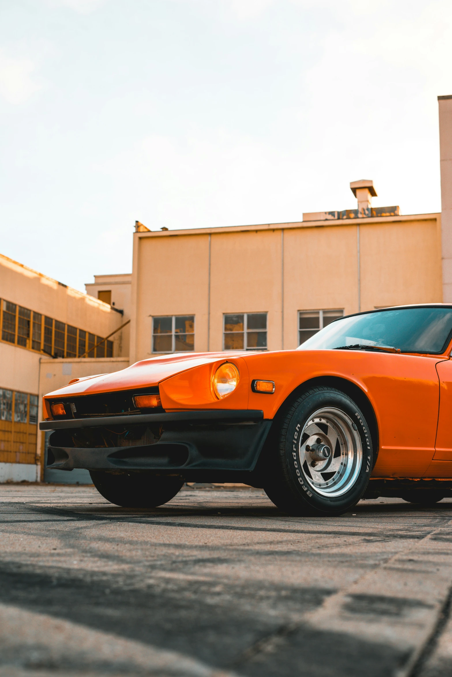 an orange sports car sitting outside of a tall building