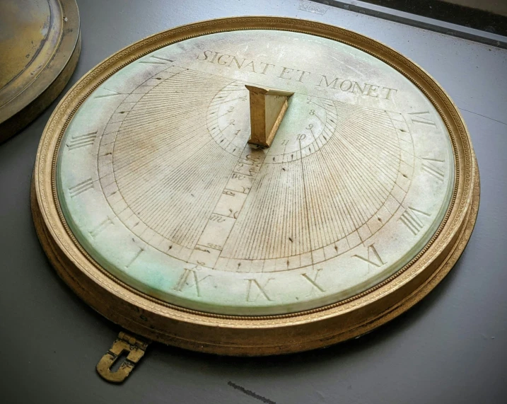 a ss clock on a grey surface with a number 1