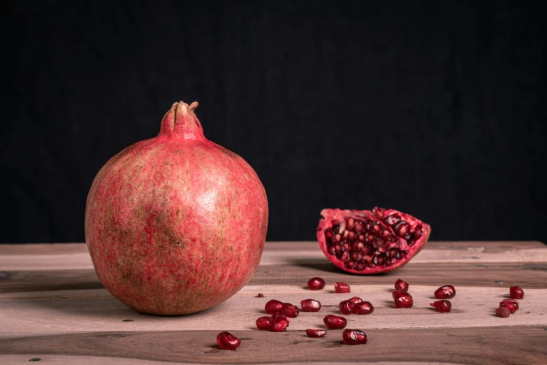 pomegranates scattered on the table and half - eaten, on black background