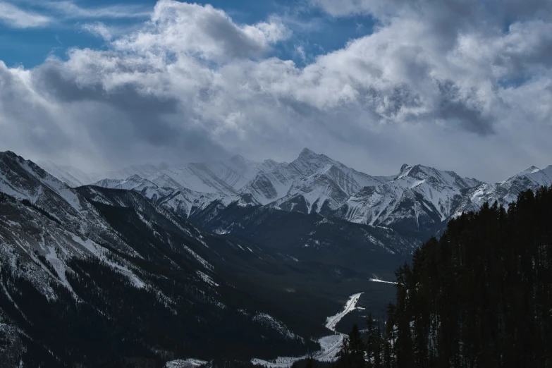 some snowy mountains under a cloudy sky and clouds