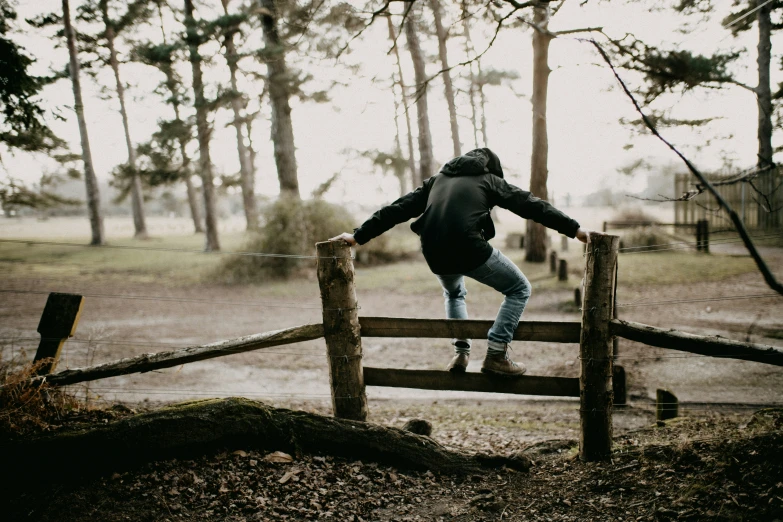 a person jumping over a fence in the forest