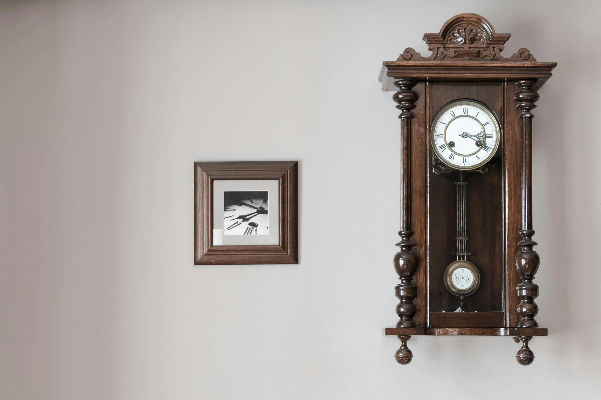 a clock mounted on a wall near a framed po