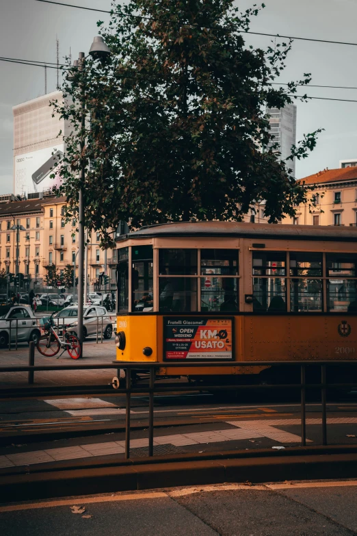 an old yellow tram driving down a street