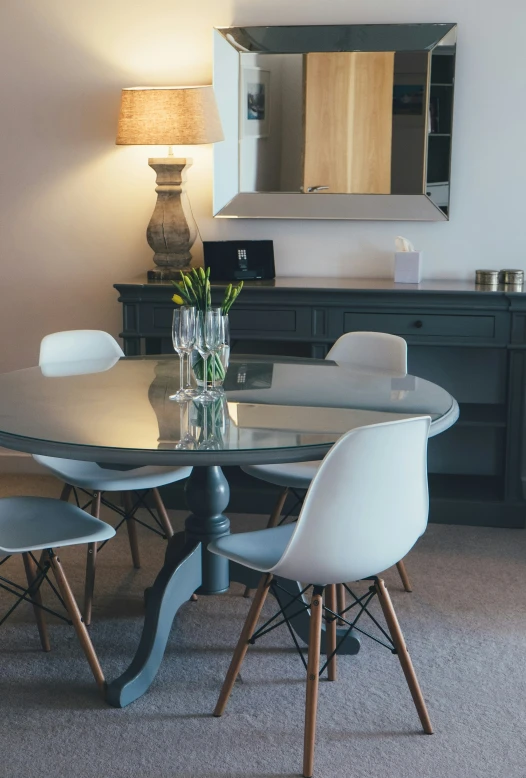 a dining room set with a glass table and chairs