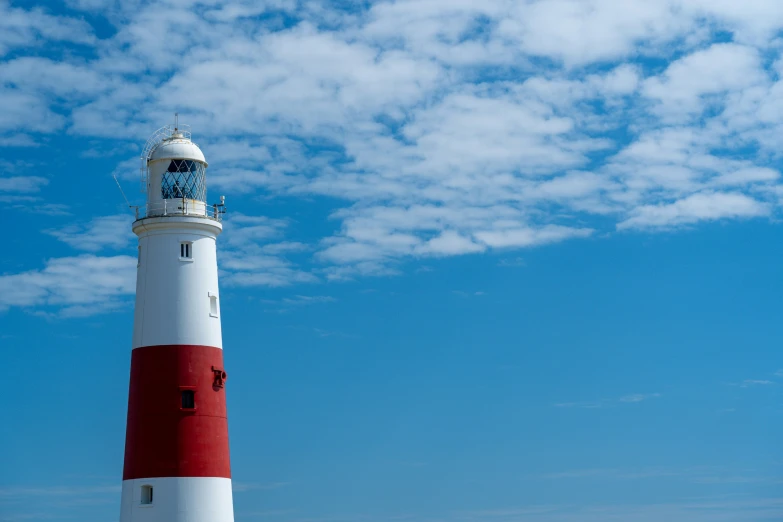 a red and white lighthouse is in the middle of blue skies