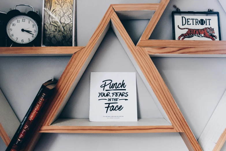 the triangular shelves are filled with pos, books, and clocks