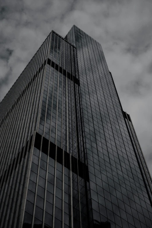 the top of a glass skyscr with several clouds overhead