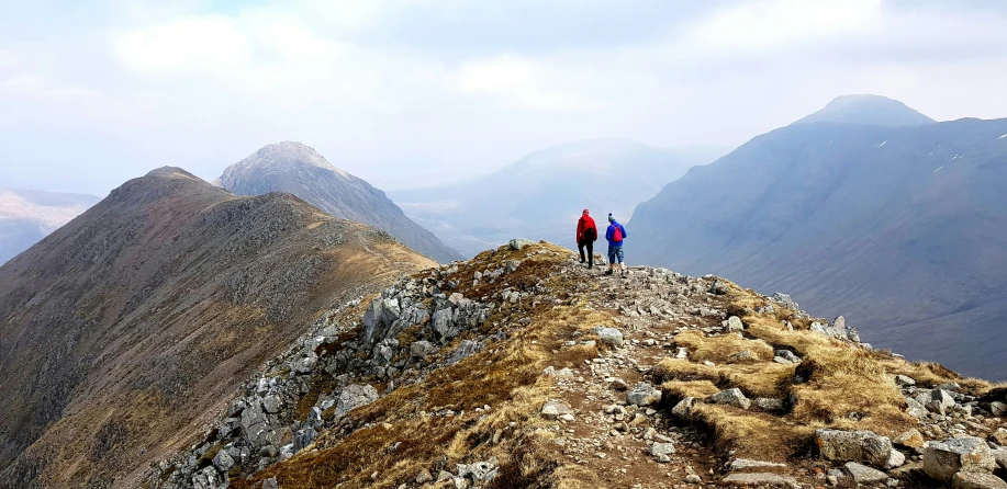 three people walking on a mountain top together