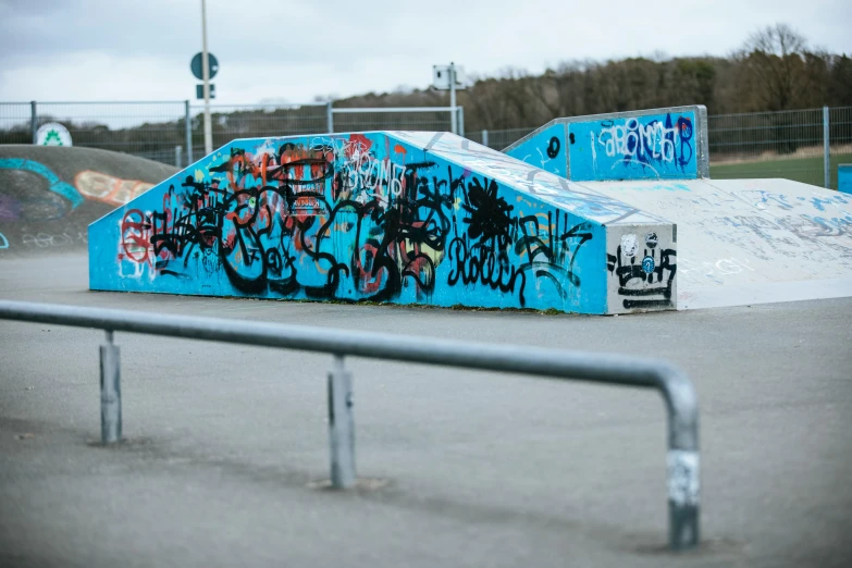 a skate park has blue ramps with spray painted graffiti