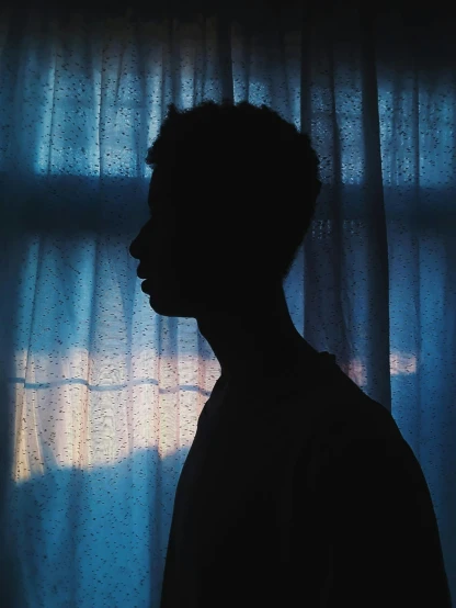 a silhouette of a person standing in front of a window