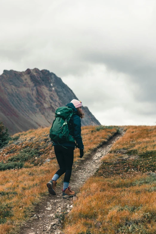 a woman is hiking up a hill towards a big hill