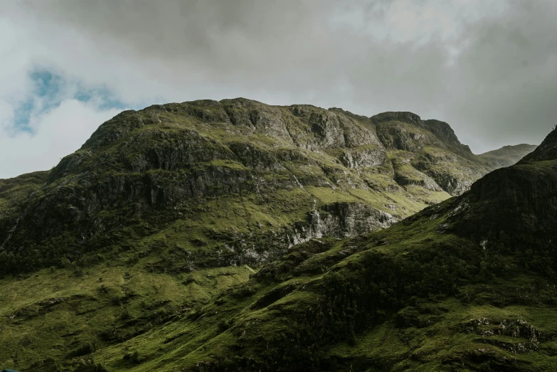 green mountains are surrounded by grey clouds in the distance