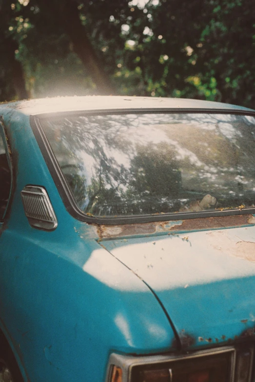 an old rusty car in front of some trees