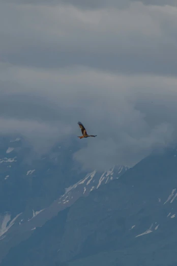 the plane is flying over the mountains with it's wings spread wide