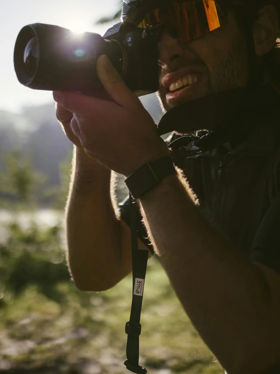 a man holding his camera taking a picture of a landscape