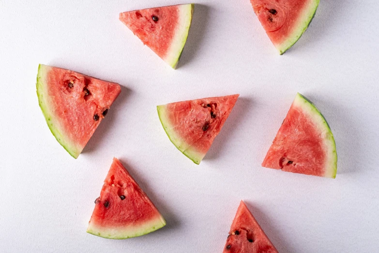 seven slices of watermelon sliced in wedges on a white surface