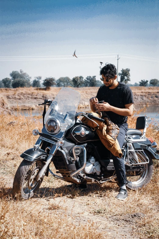 a man sits on his motorcycle and uses his cell phone