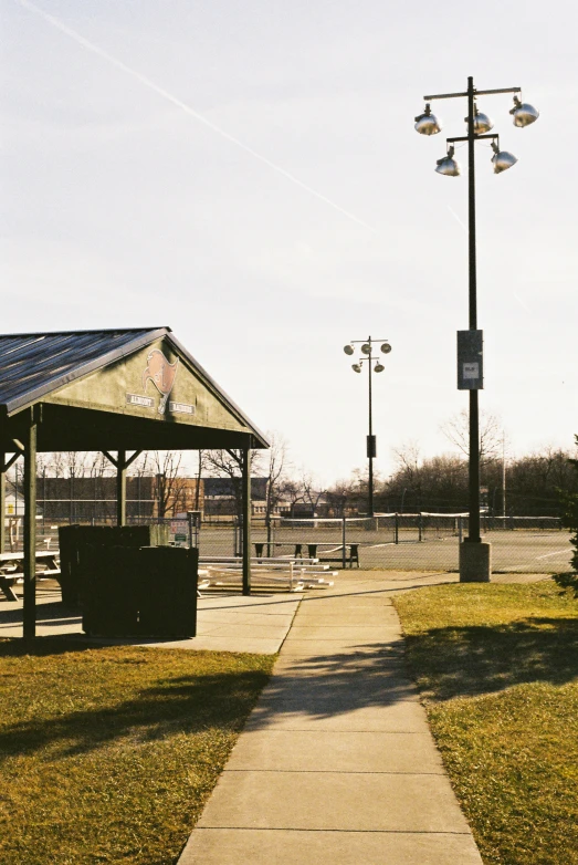 a walkway in the middle of a park with street lights