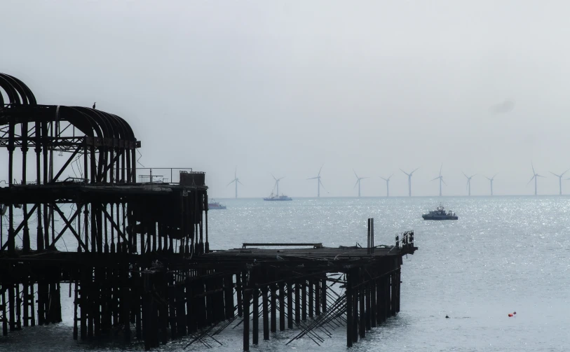 a foggy day in the ocean and wind mills