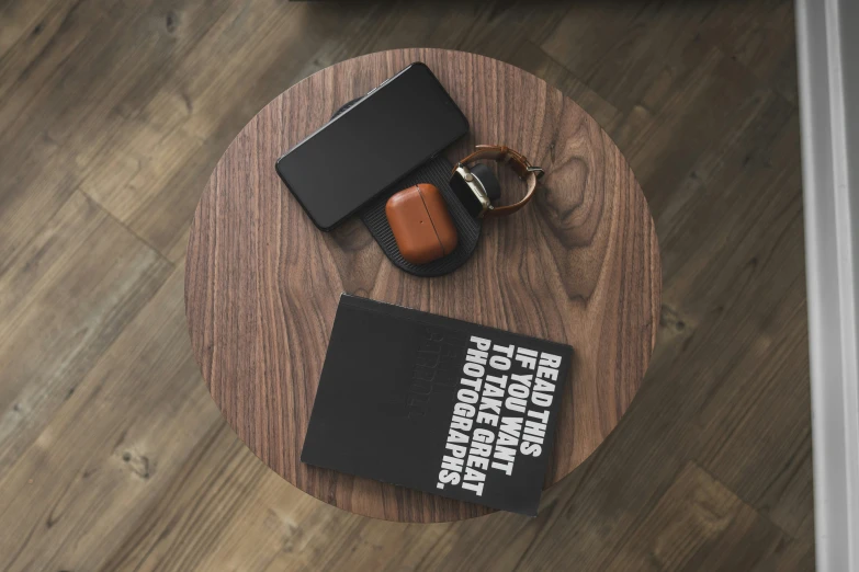 a round wooden table with a pair of reading glasses and a book on top