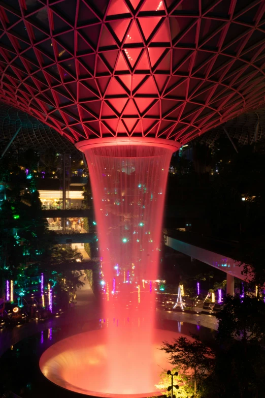 a fountain features bright pink lights in the city