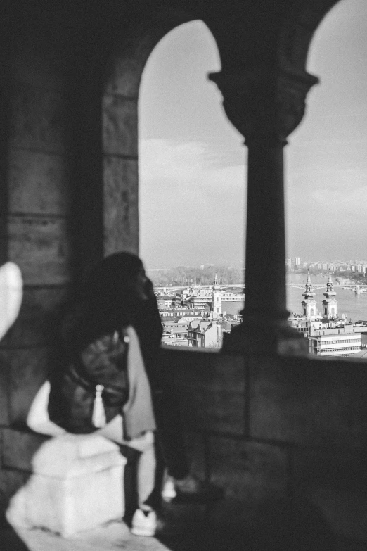 a girl sitting at a table while looking out of a window