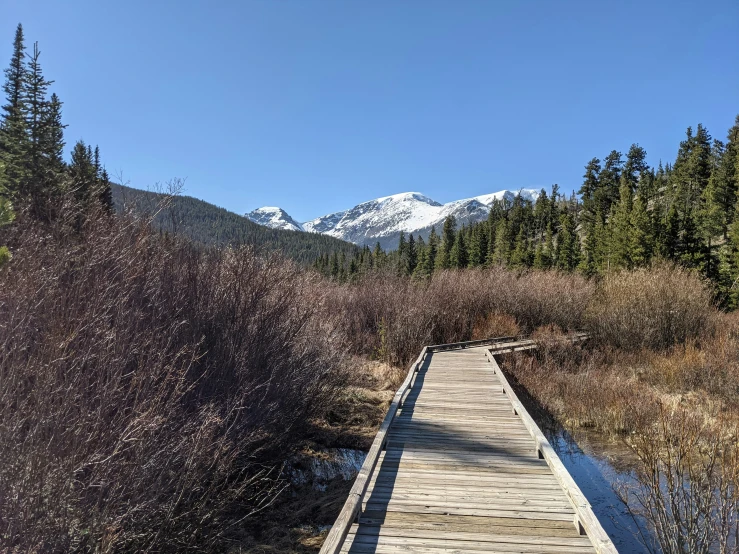 a wooden path is going over water towards mountains