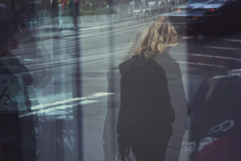 a woman stands next to an intersection with her handbag