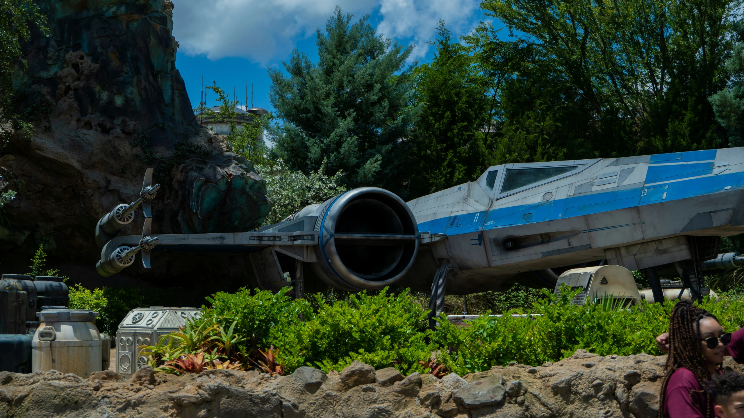 a silver and blue airplane parked near some rocks