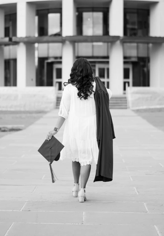 a woman in a dress holding a flower bouquet while walking toward a building