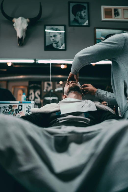 a man in grey shirt laying on top of a bed