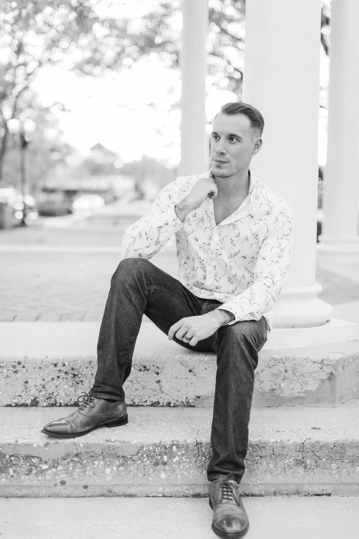 a man sits on the steps while wearing a shirt and jeans