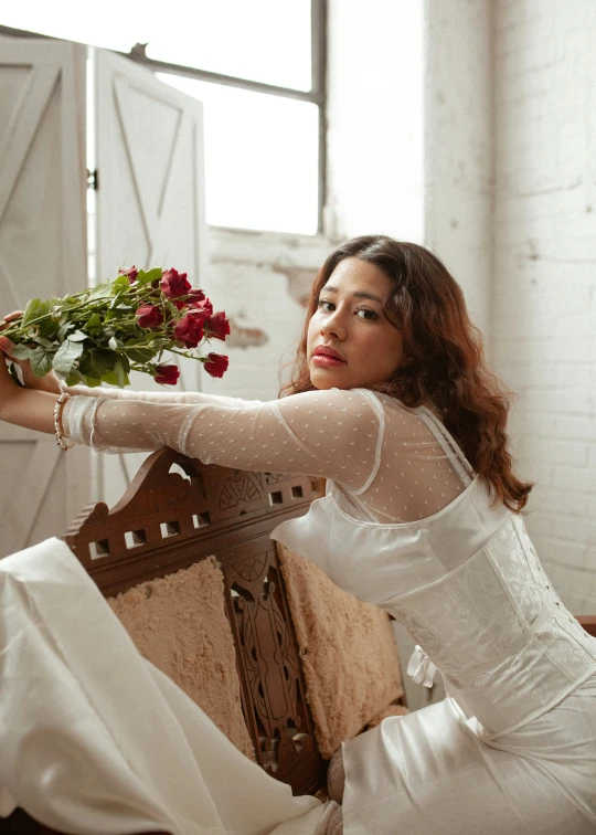 a woman in a white dress is sitting on a chair with flowers