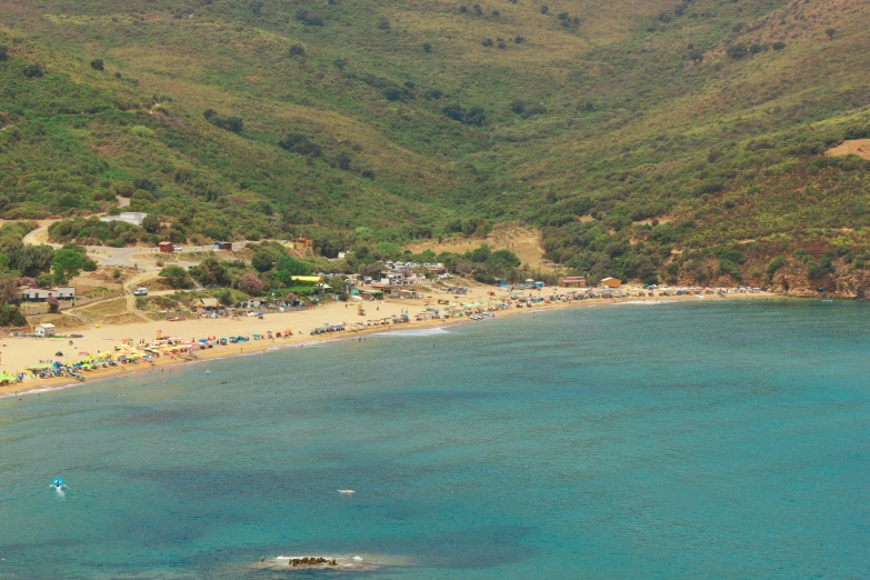 a body of water with lots of sand next to green hills