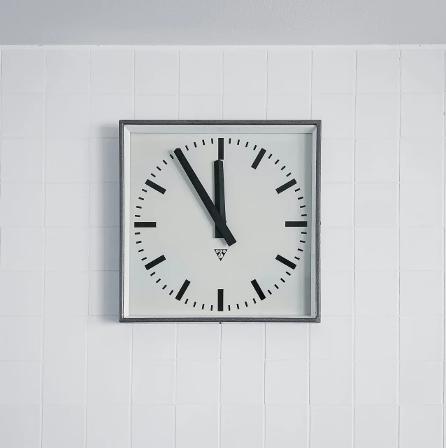 clock on white tiled wall with black and gray numbers