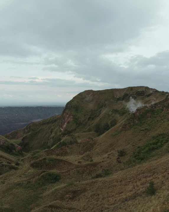 two sheep are standing on the edge of a hill