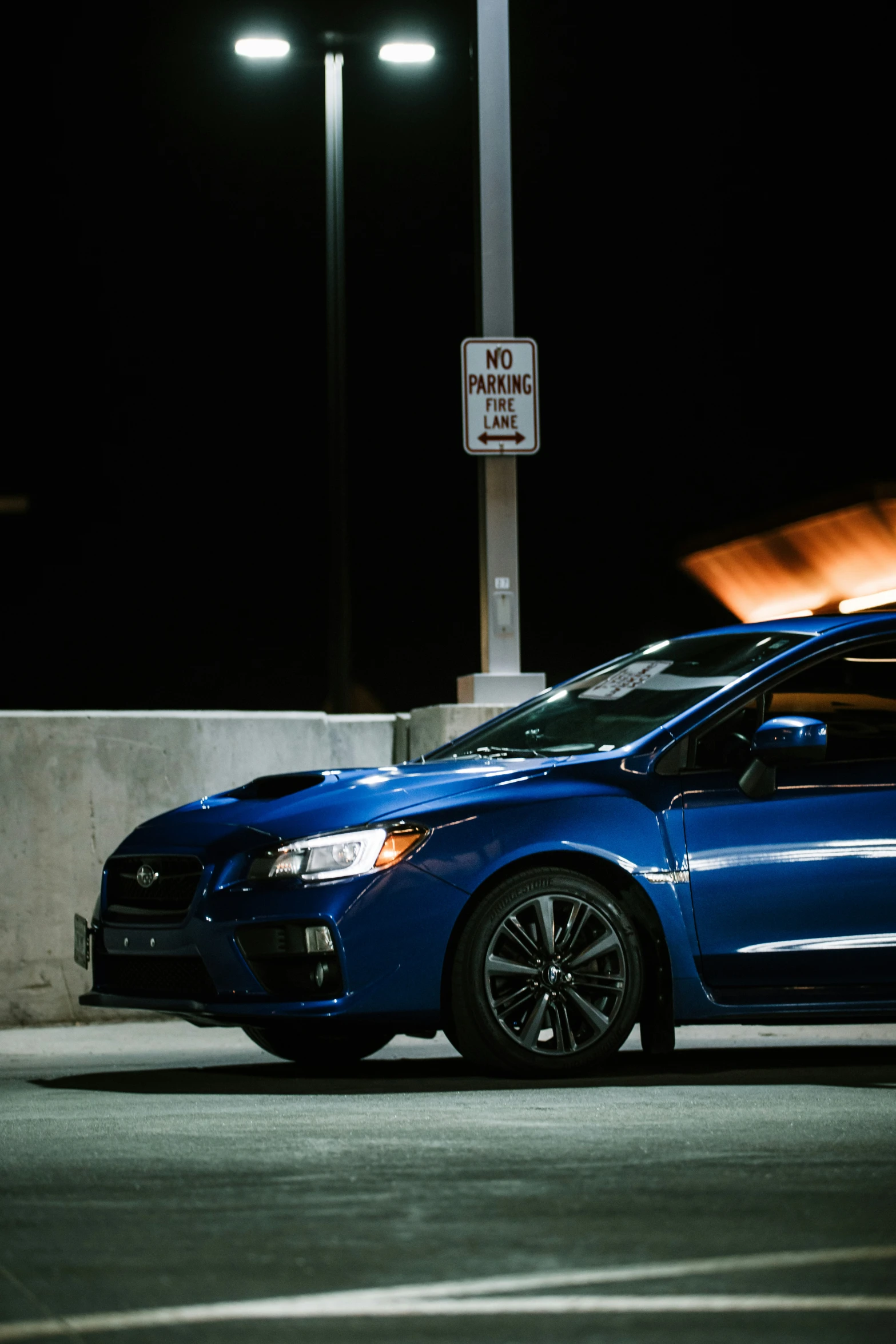 a blue car parked next to an outdoor parking sign