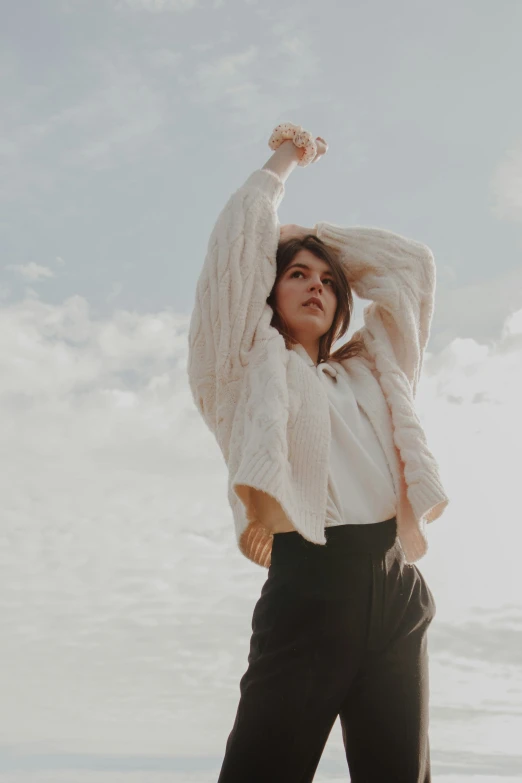 a woman is wearing a white sweater and black pants