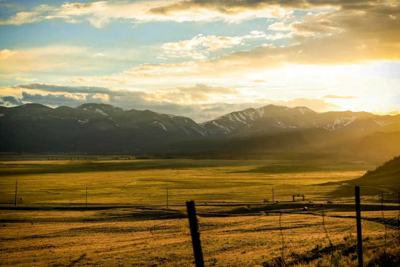 the sun sets behind a fence in an open field