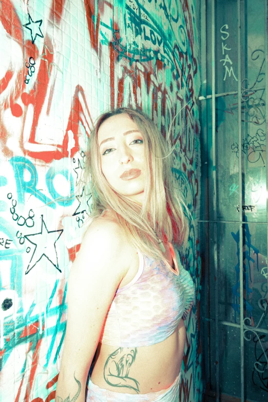 a woman in lingerie poses with wall full of graffiti