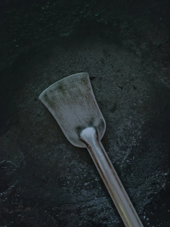 a dirty plastic ladle is in the floor of a dark room