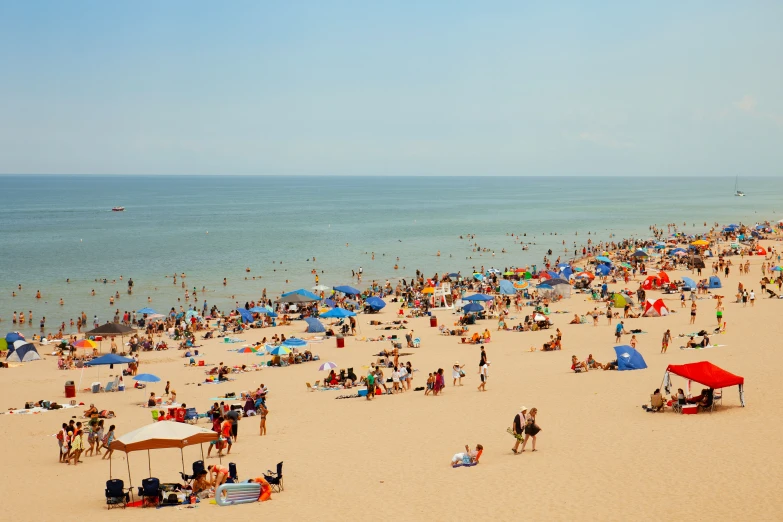 people are standing on the beach in a large group