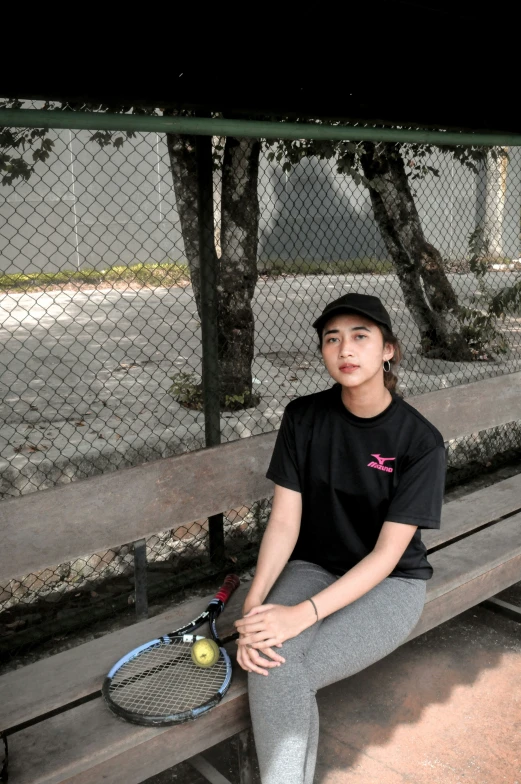 a woman sitting on top of a bench holding a tennis racquet